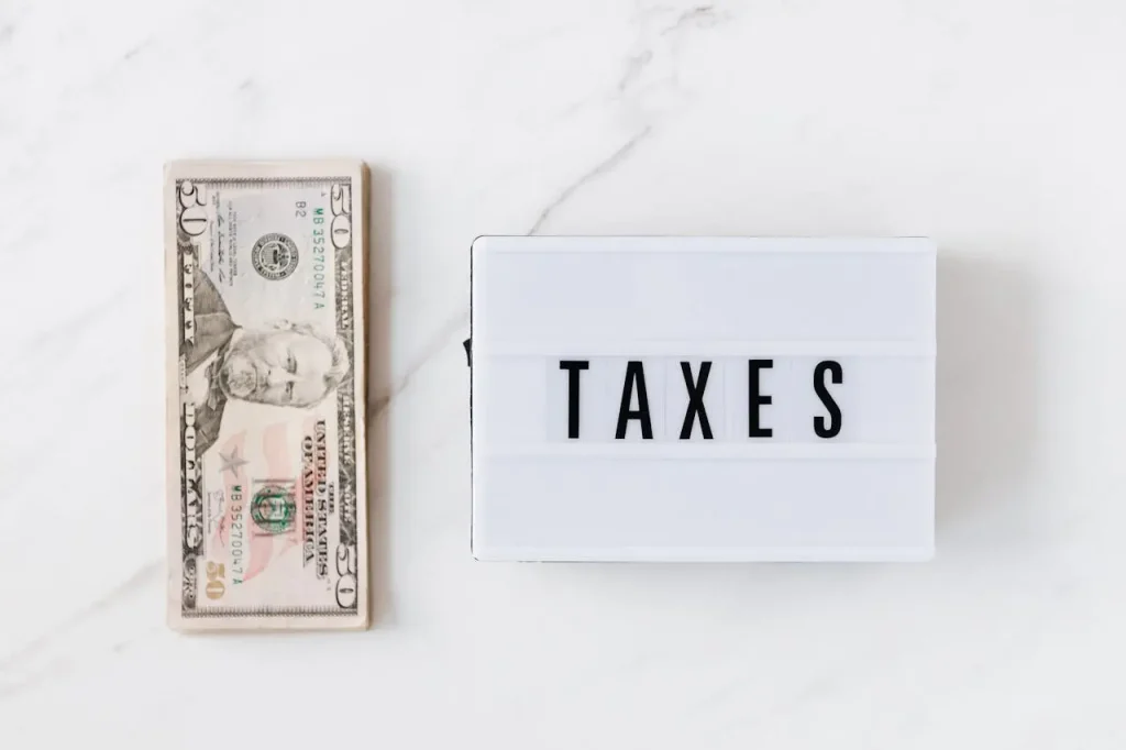 Cash on a table next to a board labeled Taxes showing the concept of are health insurance premiums tax deductible self-employed