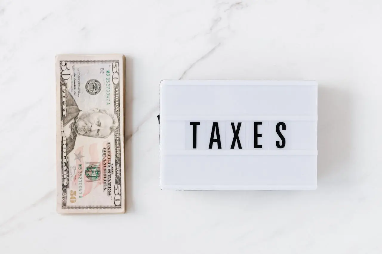 Cash on a table next to a board labeled Taxes showing the concept of are health insurance premiums tax deductible self-employed