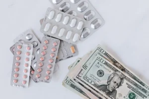 Prescription blister packs and cash representing medical expenses and health insurance alternatives